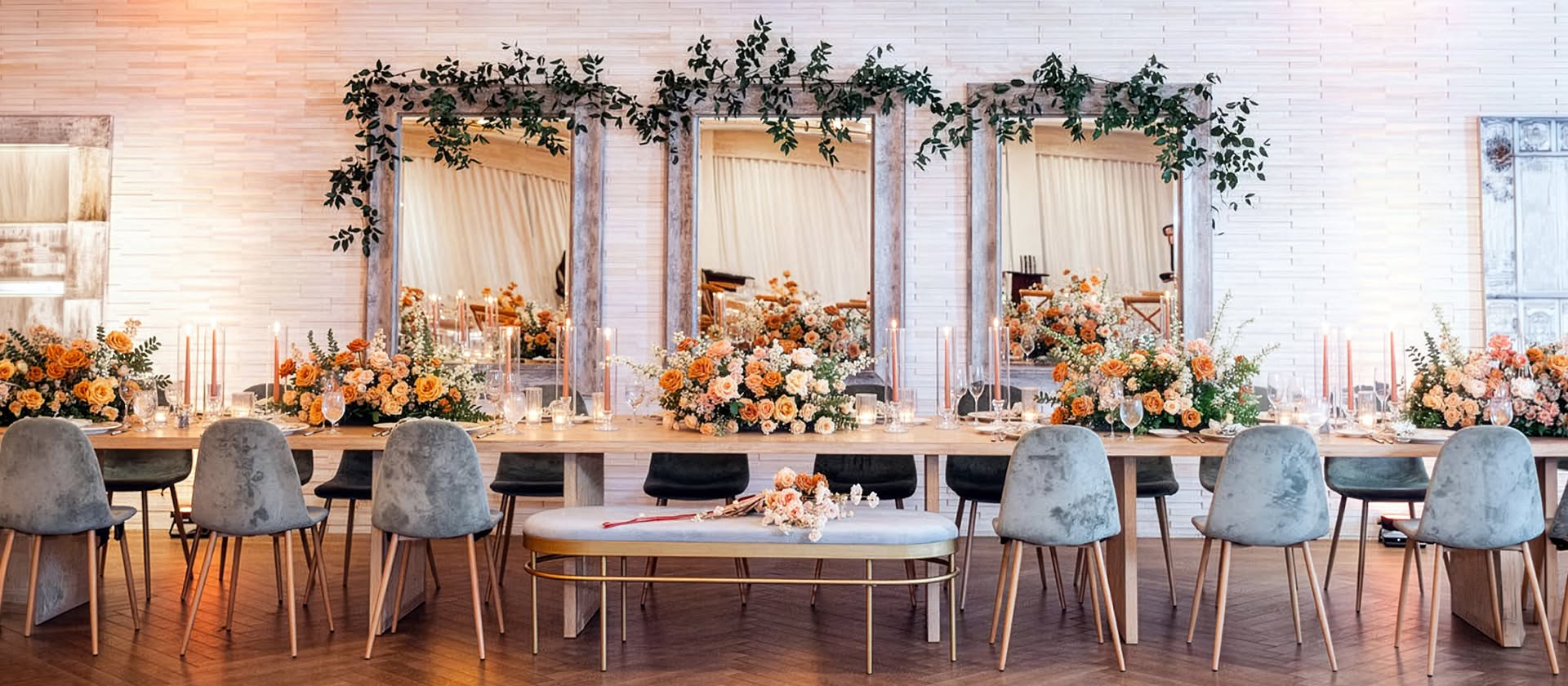 A reception head table with peach floral centerpieces and candlelight at a San Diego wedding, planned by Bliss Events.