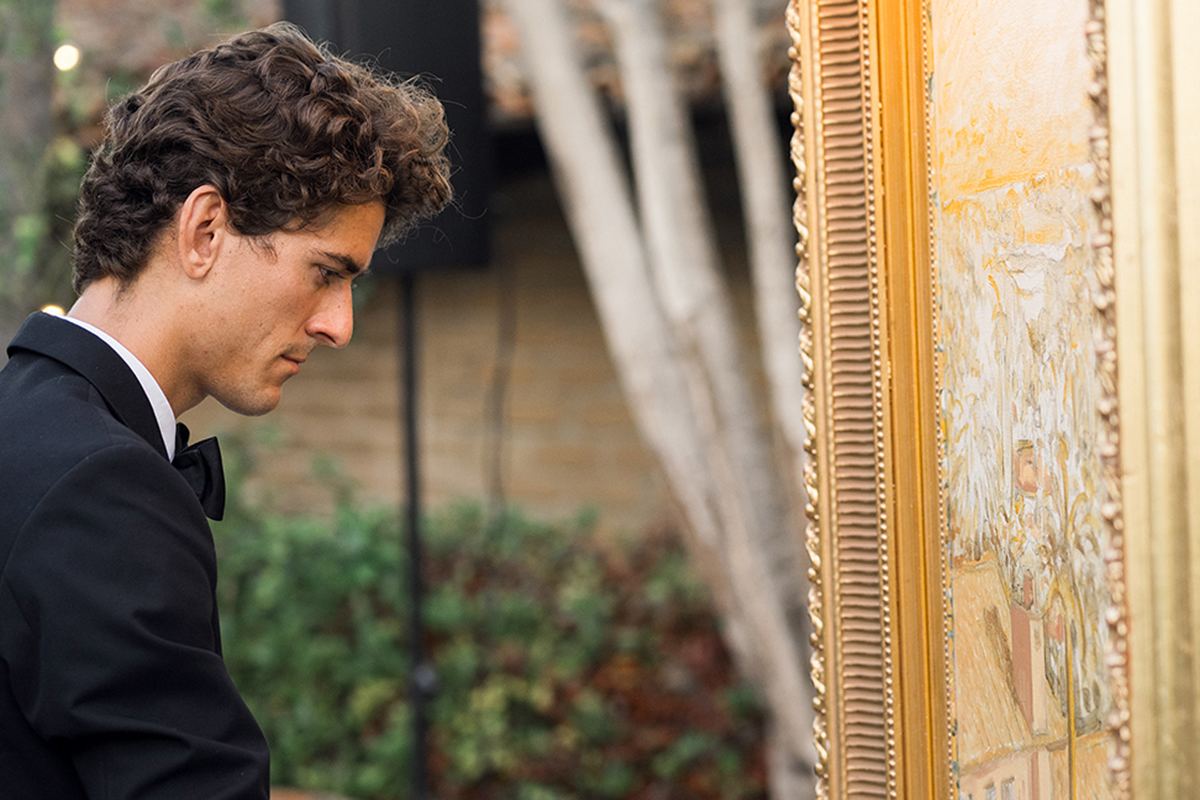 A live painter in black tie capturing the celebration in oils on a gold-framed canvas.