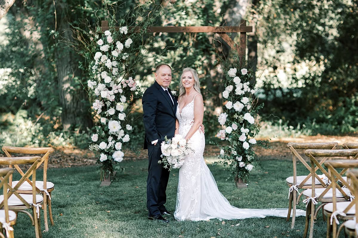 Bride and groom standing beneath a floral ceremony arch during their Temecula Creek Inn wedding.