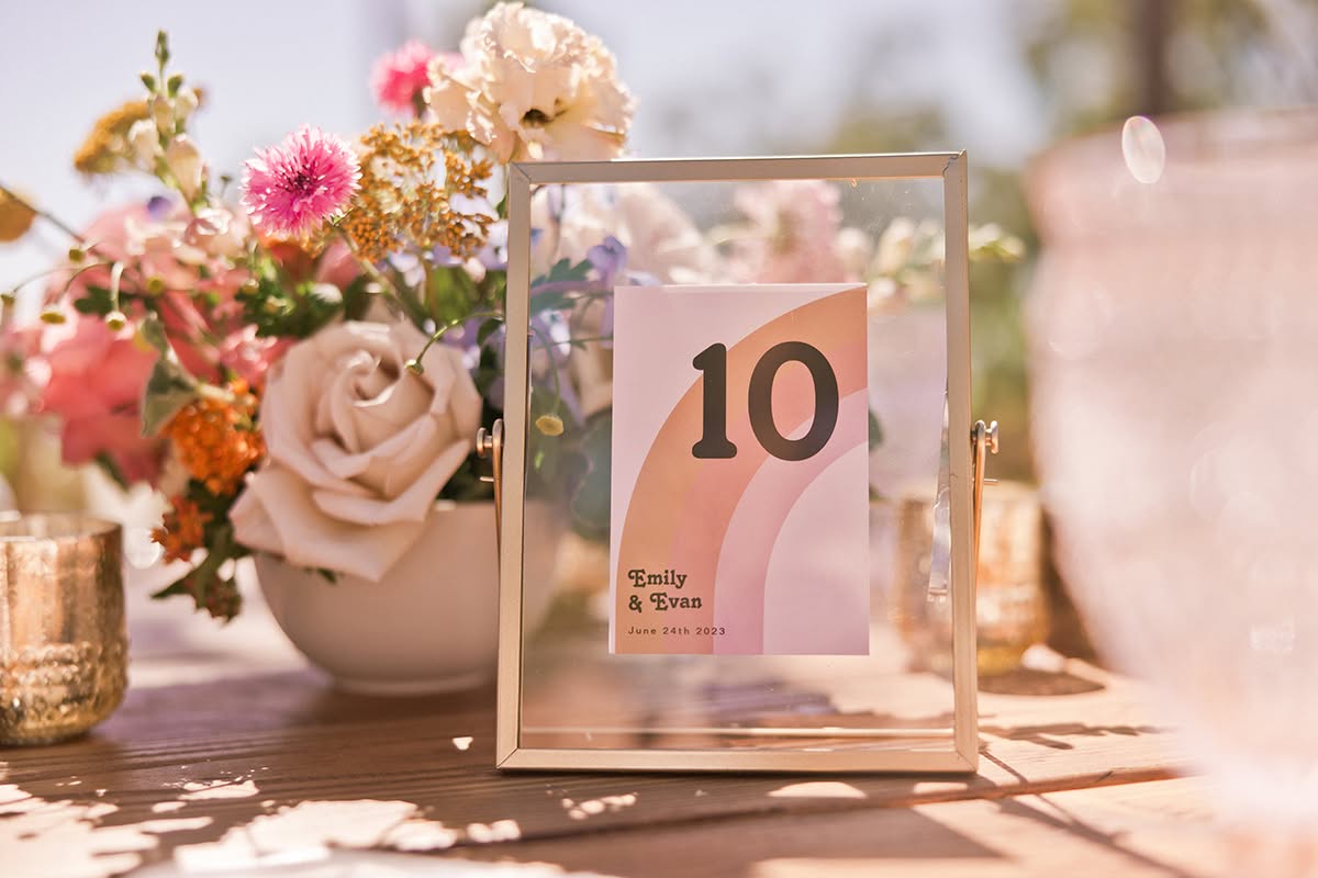 Wedding table number displayed beside colorful florals and blush table linens.