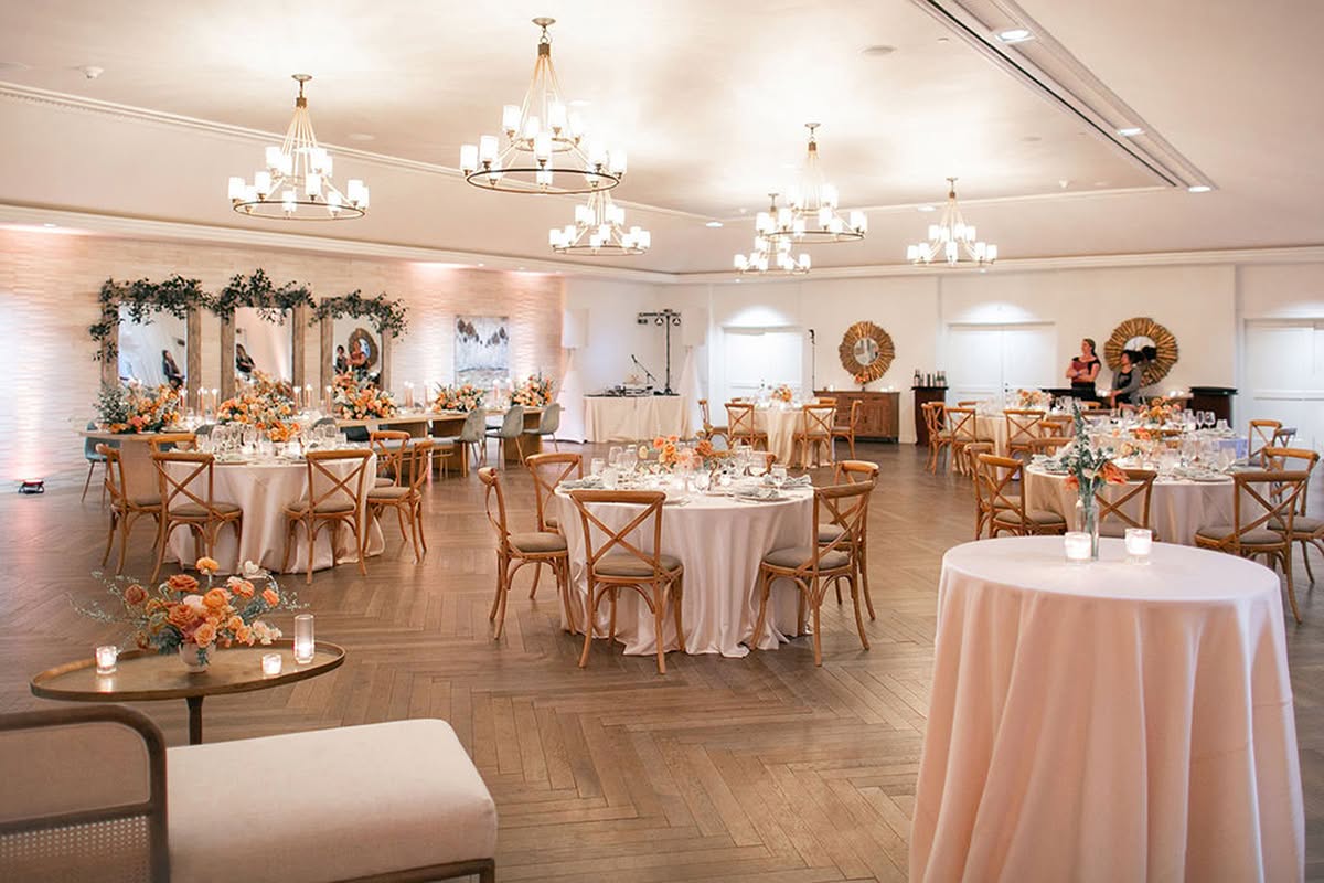 Ballroom reception with soft sunset florals, lounge seating, and warm romantic lighting.