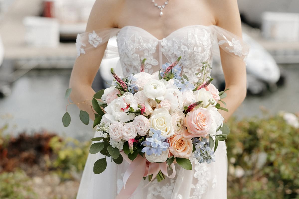 Bride holding a soft pink and white wedding bouquet near the marina at Loews Coronado Bay Resort.