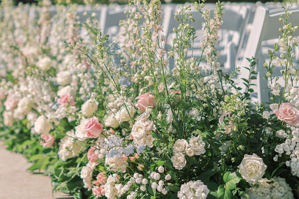 Ceremony aisle lined with soft pink and white florals at Hotel del Coronado.