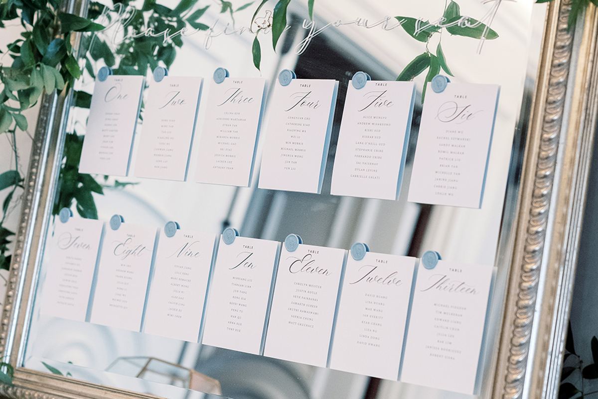 Mirror seating chart accented with greenery for an elegant wedding reception.