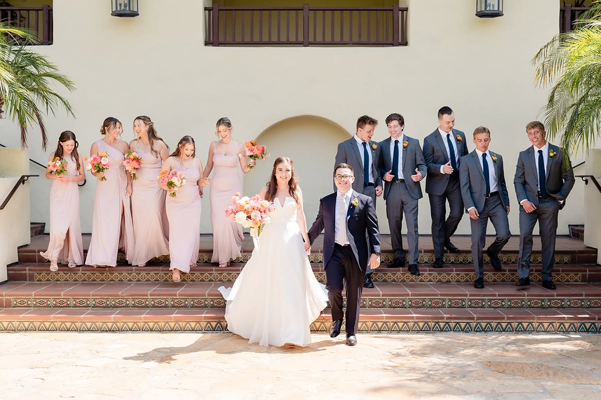 Katie and Jake walk with their wedding party on the steps at Estancia La Jolla Hotel & Spa.