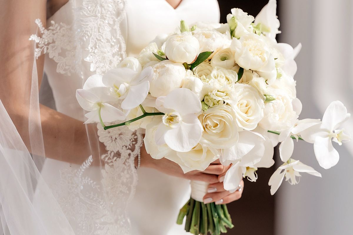 Bride holding a white bouquet with veil details before her ceremony.