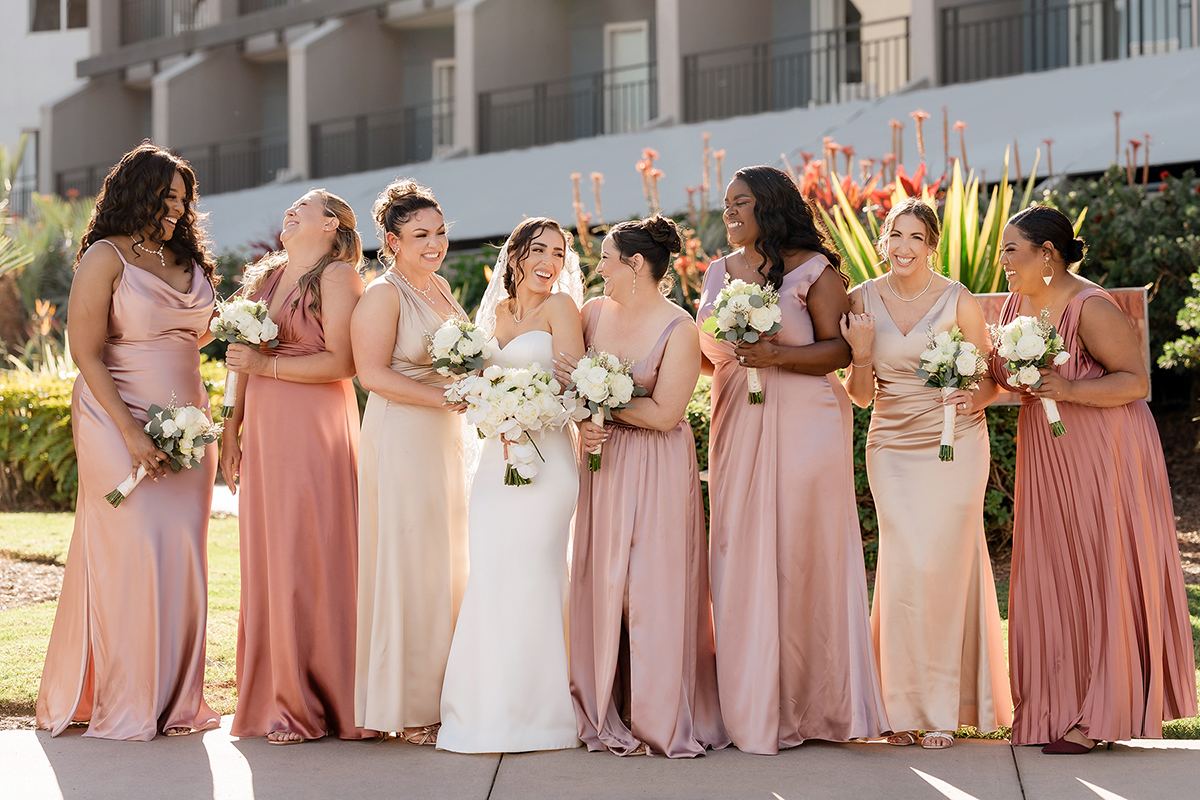 Bride laughing with bridesmaids in blush dresses during wedding party portraits.