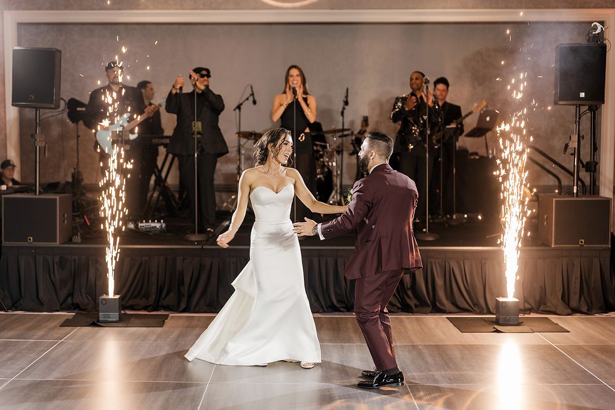 Bride and groom dancing in front of a live band with spark effects.