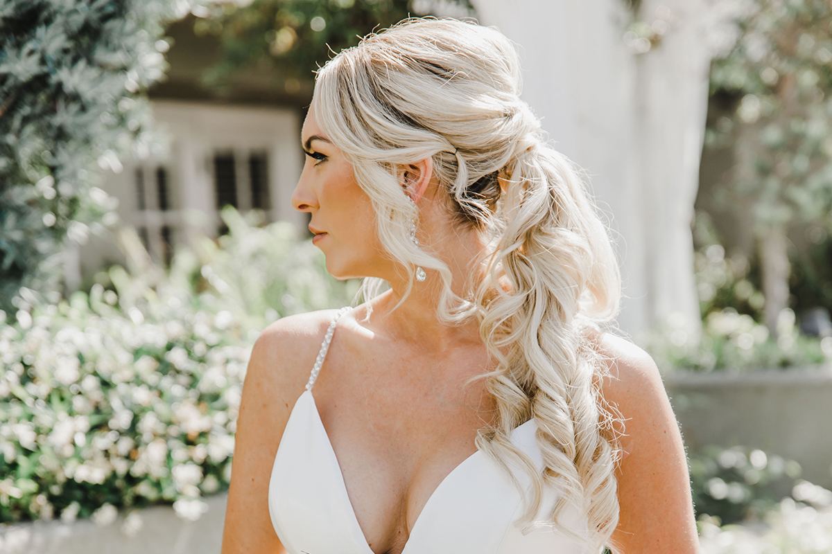 Bride holding a white bouquet before her seaside wedding ceremony.