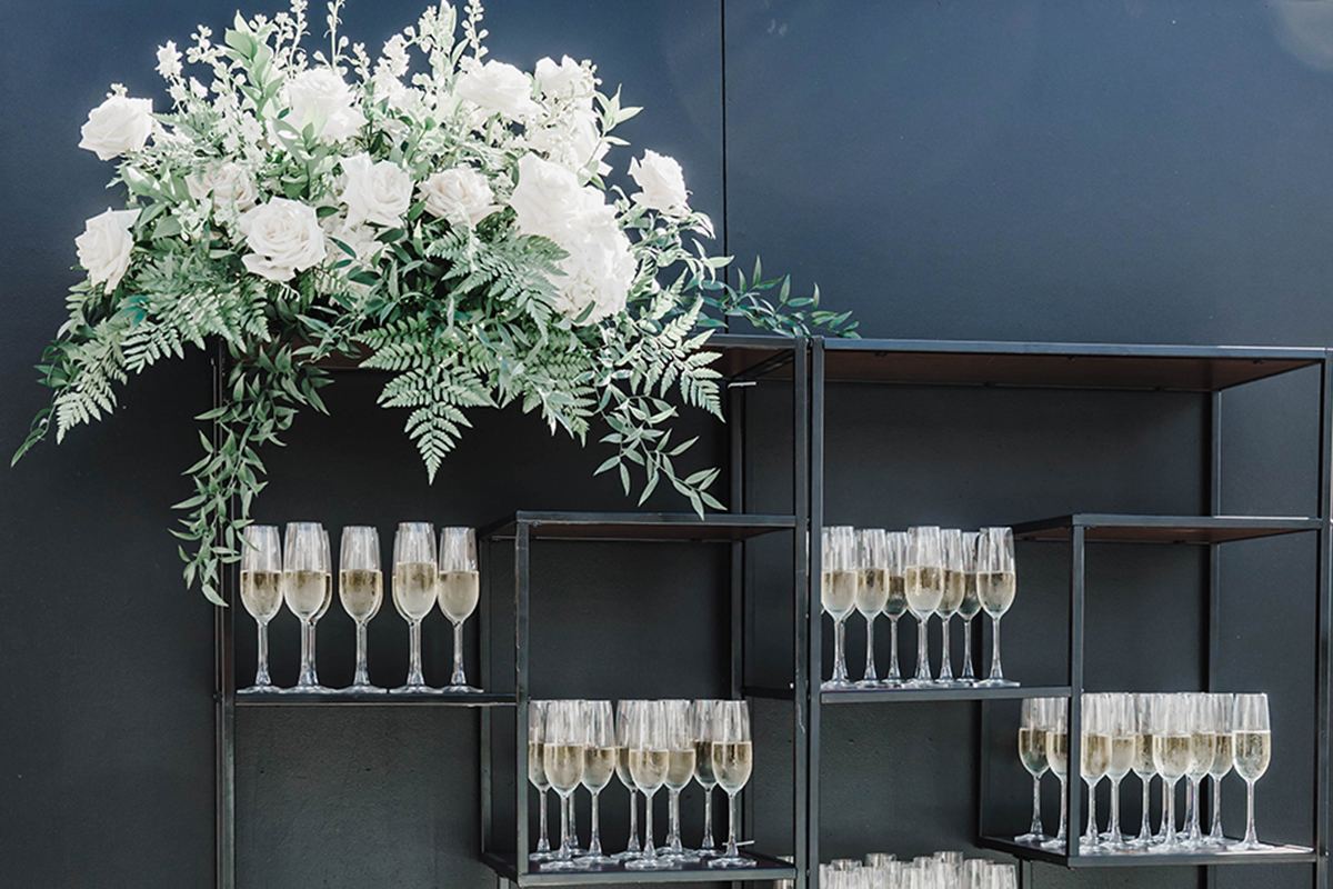 Black champagne display with white florals and rows of champagne glasses.