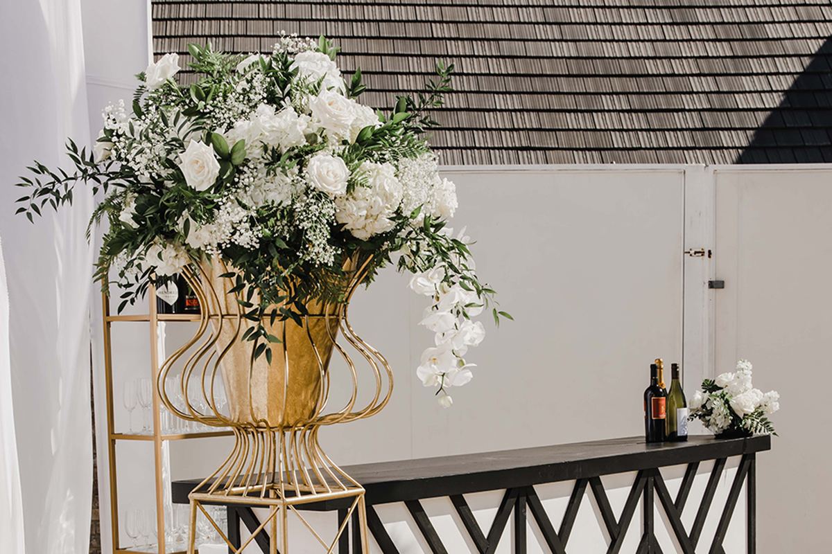 Black-and-white geometric bar with a white floral arrangement on a gold stand.