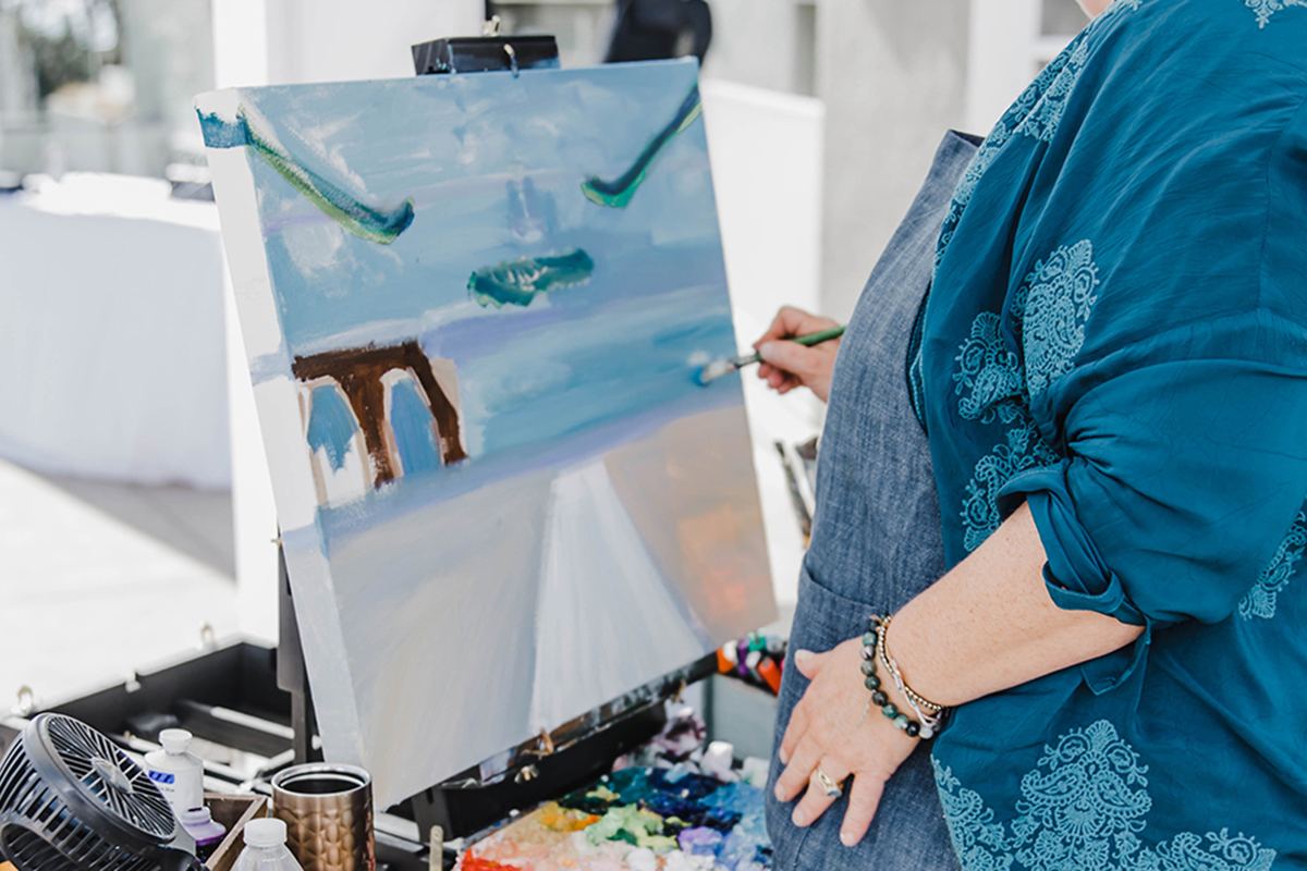 A live painter working on a painting of the rooftop ceremony during Tara and Brad’s celebration.