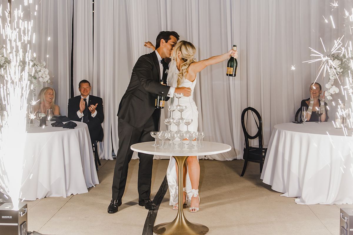 Bride and groom celebrating with a champagne tower and spark effects.