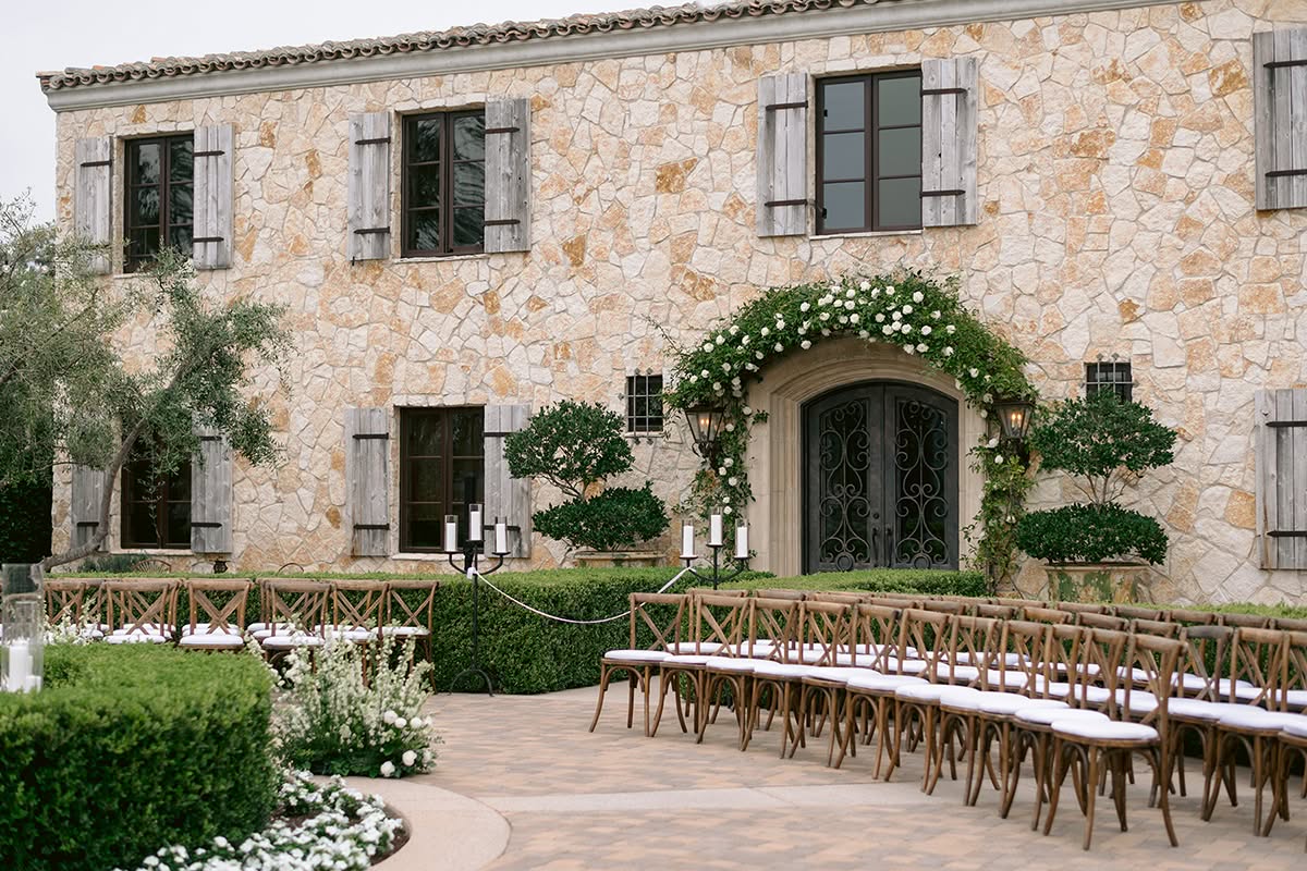 Long courtyard dinner table with white florals and the stone chateau behind.